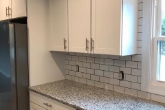 white-subway-tile-in-kitchen-backsplash-from-counter-to-cabinets-around-window